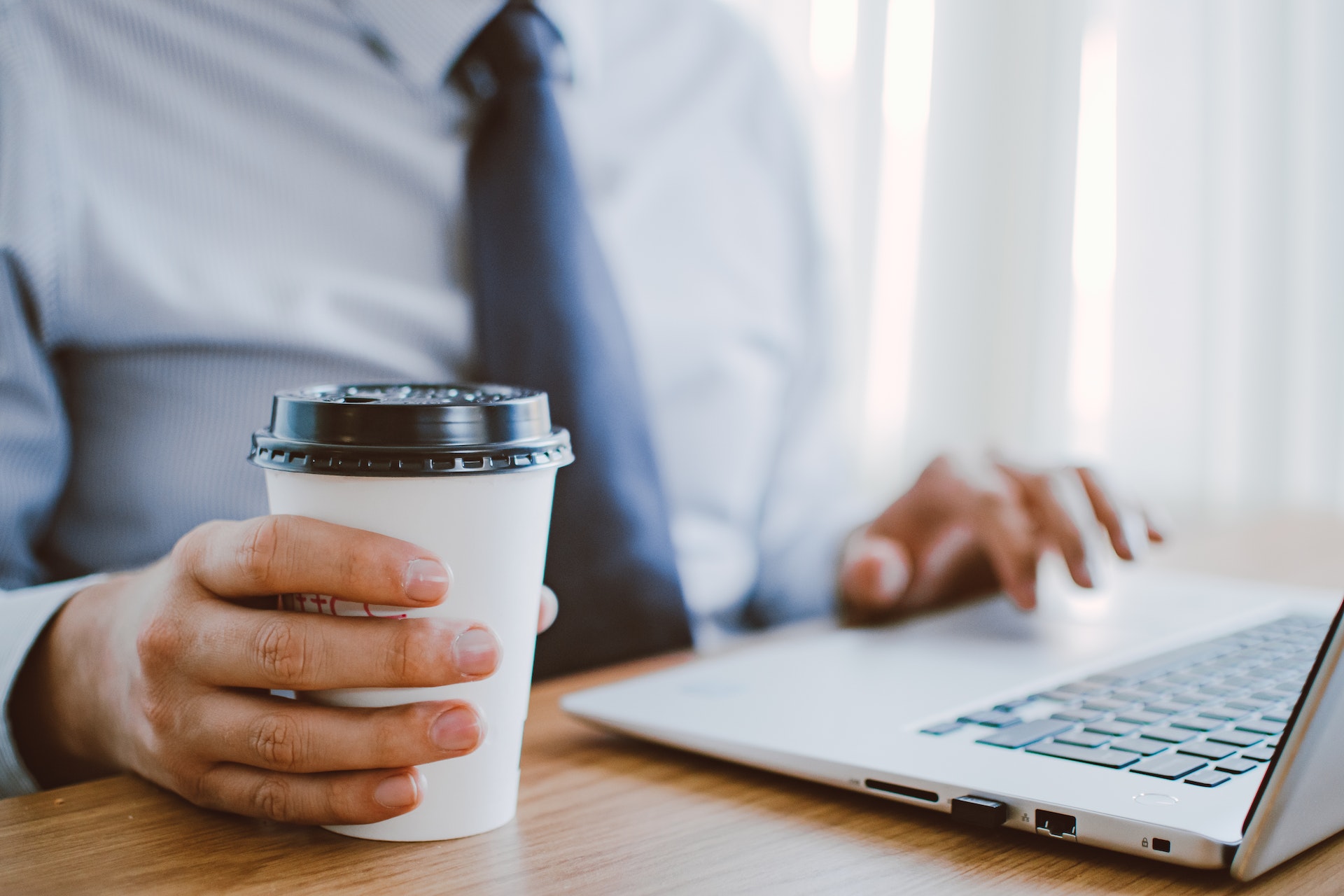 Man with coffee and laptop. Image by Lisa Fotios via Pexels.