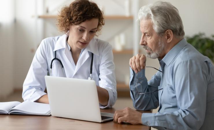 A doctor and senior patient looking at a laptop screen together. Image by fizkes via Shutterstock.