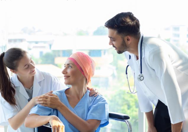 Woman with cancer speaking with doctors. Image by Nutnutchar NAV via Shutterstock