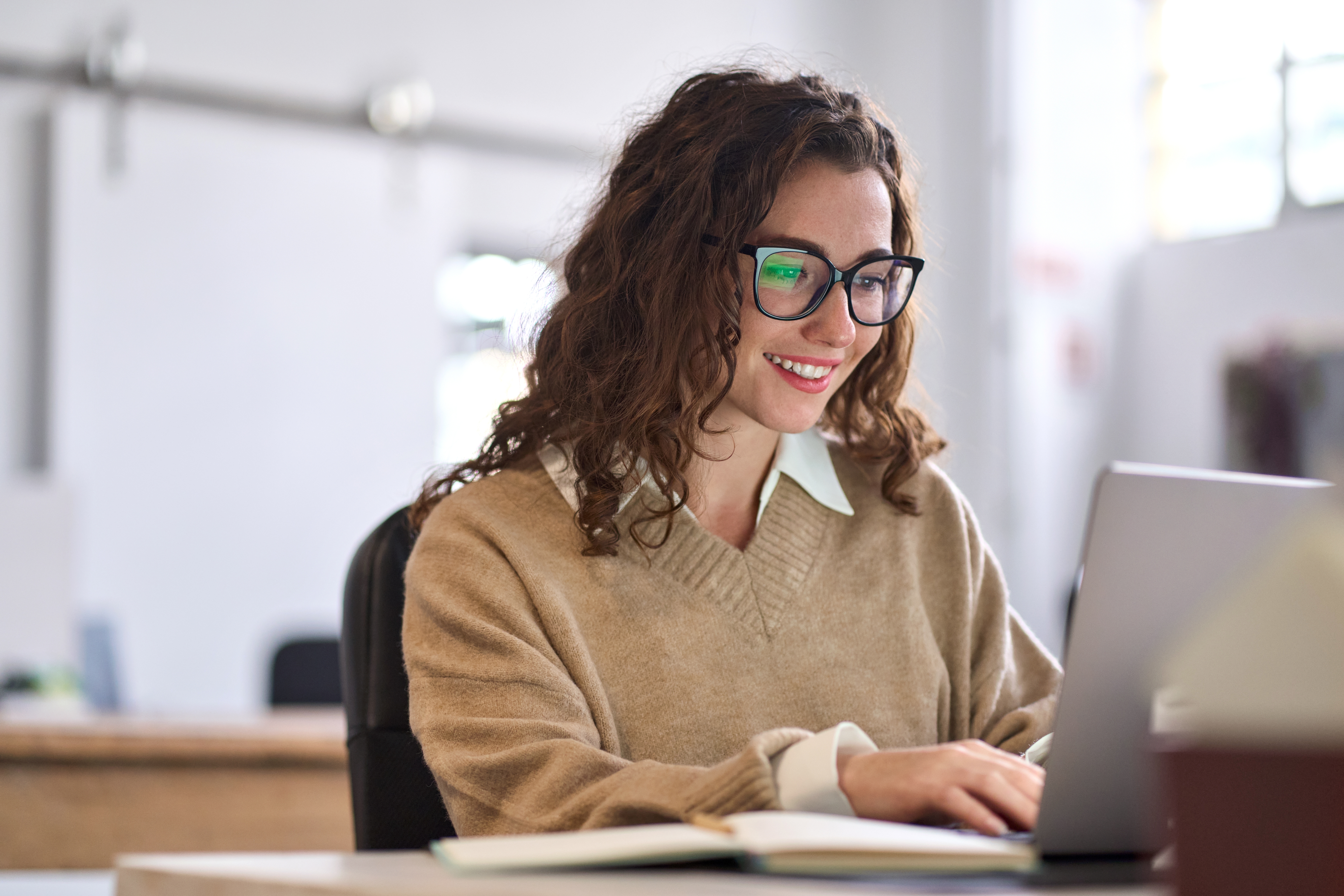 Smiling female student using computer technology learning online, doing web research.