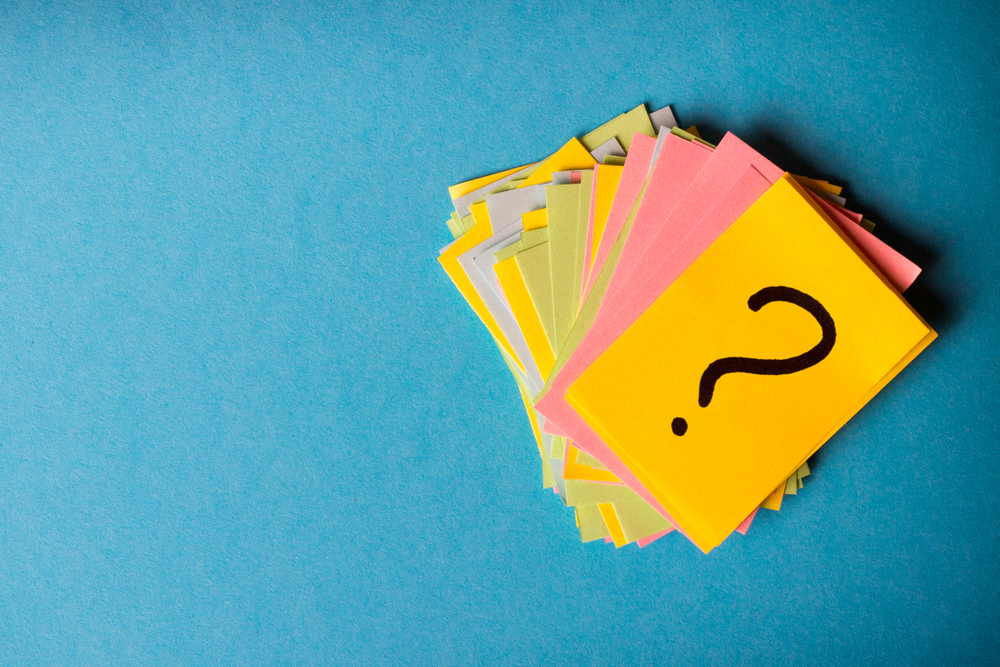 Question marks on a pile of Post-Its. Image by SNeG17 via Shutterstock.