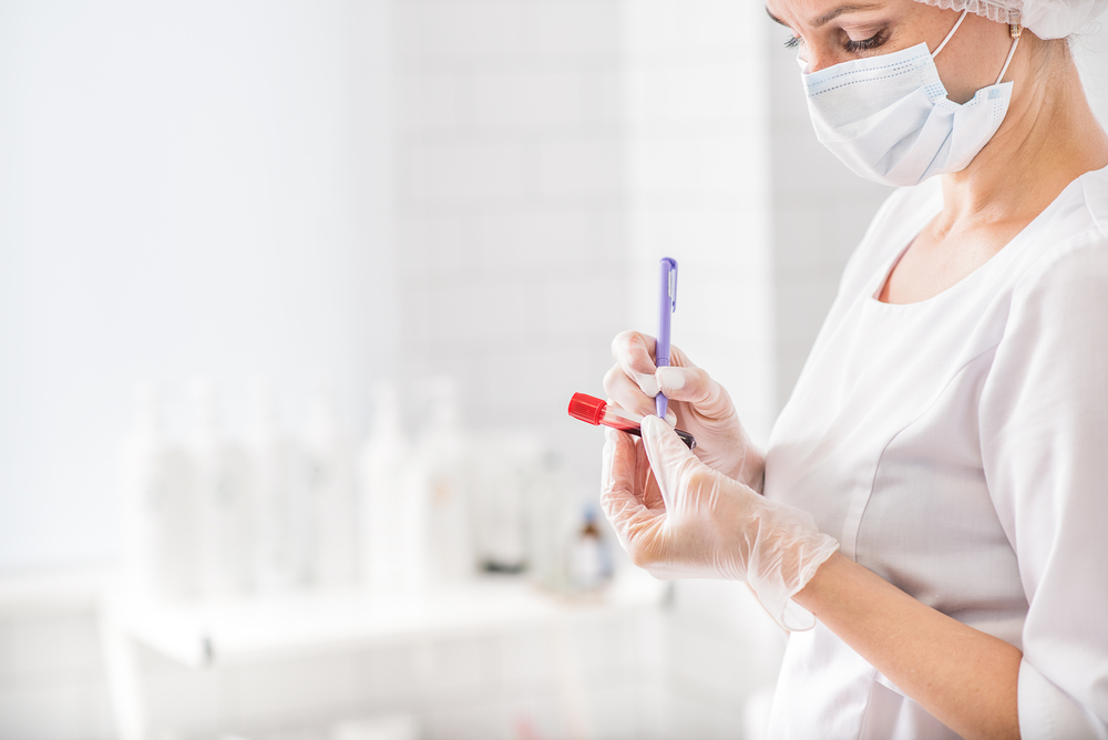 Female nurse writing on a blood test vial. Image courtesy of lena Yakobchuk via Shutterstock