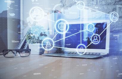 Image by Peschkova via Shutterstock. Computer on desktop with social network hologram.