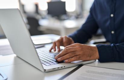 Bearded man hands typing on laptop keyboard.
