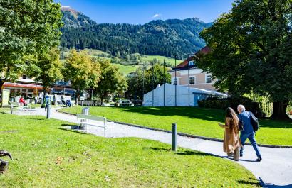 Two participants walking toward the European Health Forum Gastein venue with mountains behind