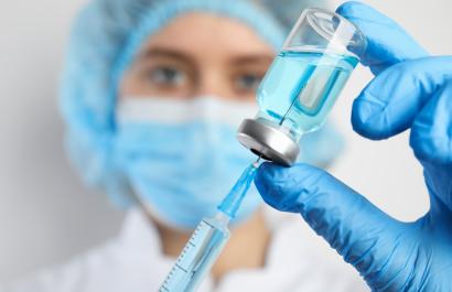 Doctor filling syringe with medication, closeup. Vaccination and immunization. Image by New Africa via Shutterstock