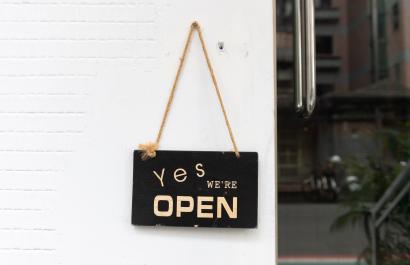 Sign hanging on a board that reads 'Yes we're open'. Image by Robbin Lee via Shutterstock