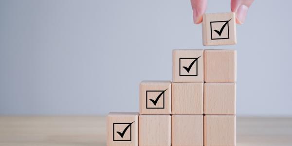 A set of wooden blocks, rising in height, with a tick at the top of each column to show regulatory approval of health research results.