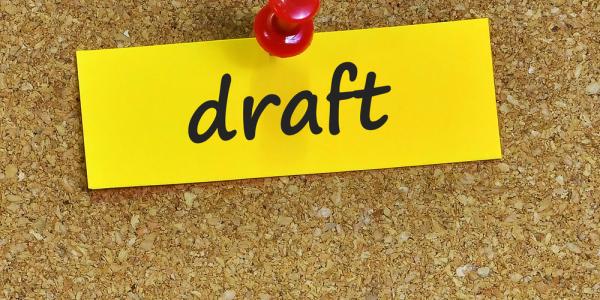 Draft written on yellow paper, pinned to a cork board, shows health research funding opportunities