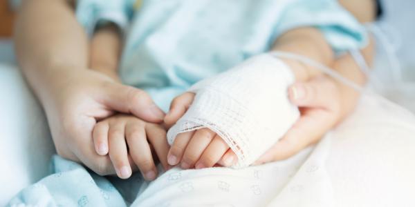 A mother holding a child's bandaged arm. Image credit: Kunlathida6242 via Shutterstock.