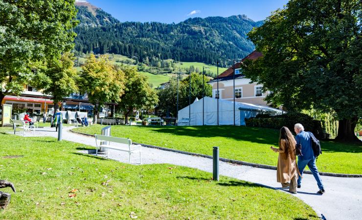 Two participants walking toward the European Health Forum Gastein venue with mountains behind