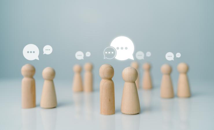 Little wooden figurines talking to each other, representing networking. Image by THEBILLJR via Shutterstock.