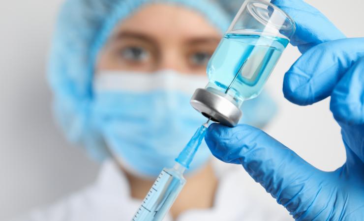 Doctor filling syringe with medication, closeup. Vaccination and immunization. Image by New Africa via Shutterstock