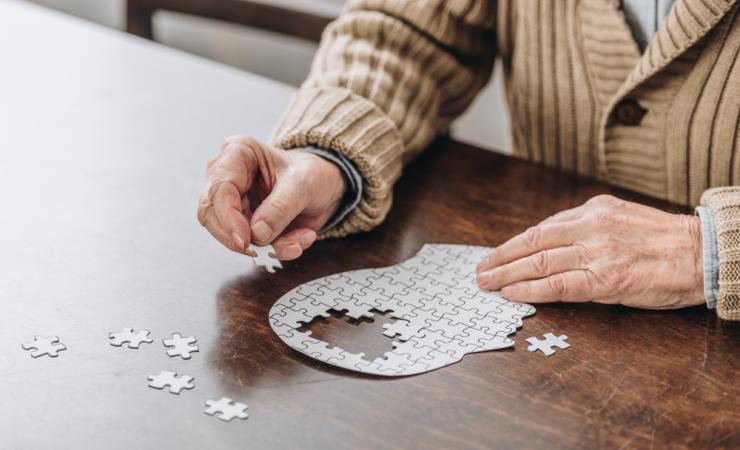 A man doing a jigsaw puzzle of a brain, symbolising Alzheimer's disease.