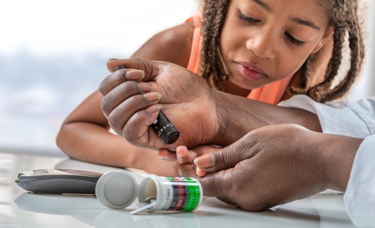 Child learning how to use a glucometer. Image credit: Adobe Stock