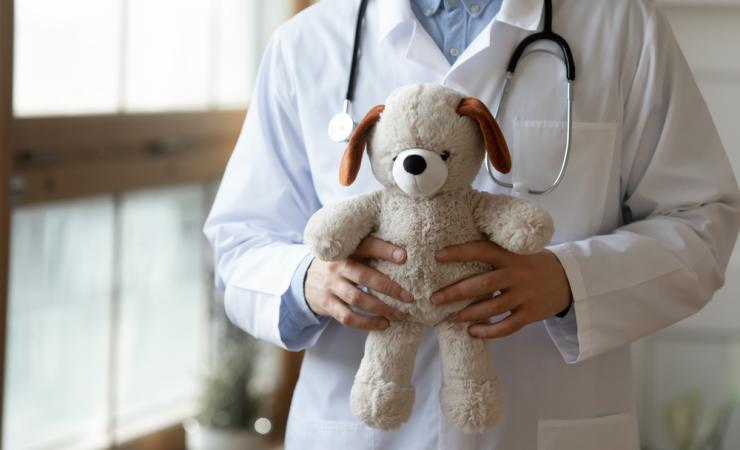 Healthcare professional in a white coat holding a plush toy dog