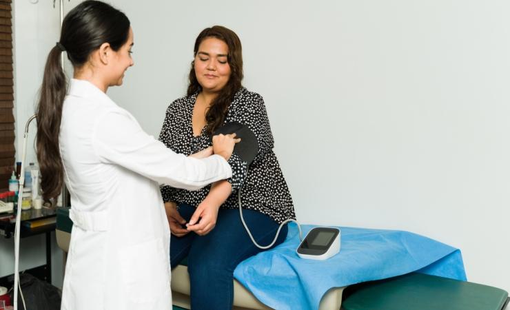 A healthcare worker measuring a patient's blood pressure, a common complication of obesity.
