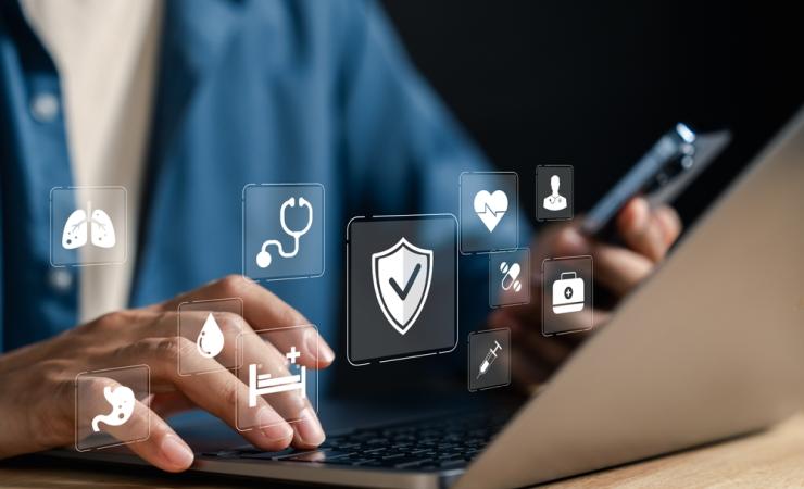 A person typing on a laptop. Health icons float above their hands, symbolising health data sharing.