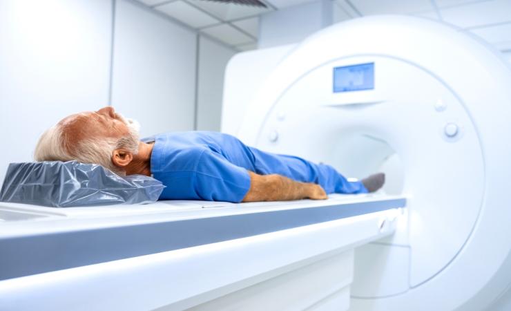 An elderly man who is about to have an MRI scan. He has white hair and a beard and is wearing what looks like blue, hospital issue pyjamas.  Image by Aleksandar Malivuk via Shutterstock