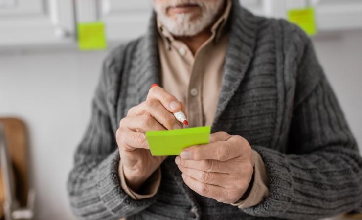 A man with memory problems due to early stage Alzheimer’s disease makes a note.