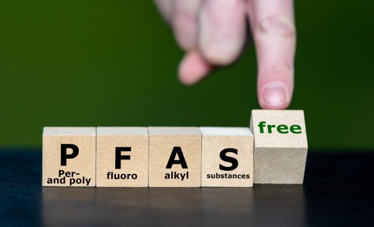 Wooden blocks spell PFAS and a finger turns a block that says ‘free’. We need to remove PFAS from health.