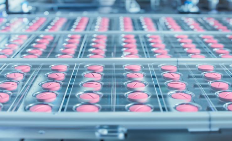 Pink pills rolling off the production line. Image by IM Imagery via Shutterstock.
