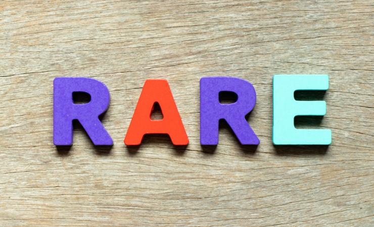The word RARE written in colourful blocks, lying on a wooden surface. Image by Bankrx via Shutterstock.