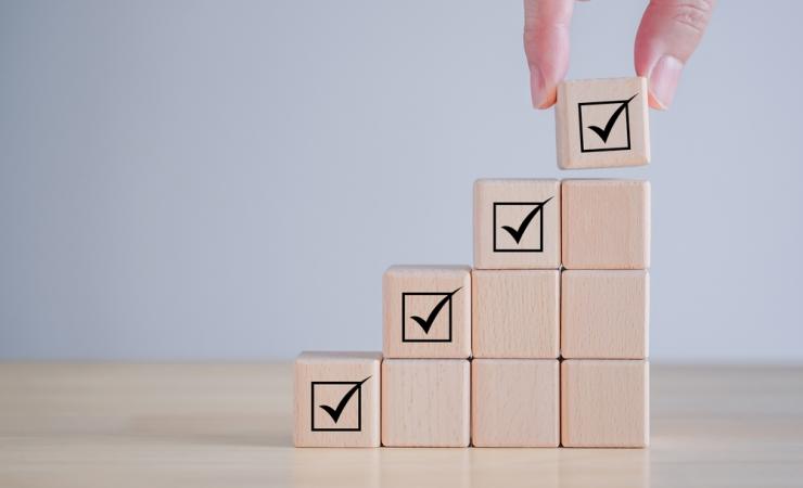 A set of wooden blocks, rising in height, with a tick at the top of each column to show regulatory approval of health research results.