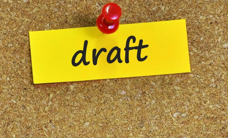 Draft written on yellow paper, pinned to a cork board, shows health research funding opportunities