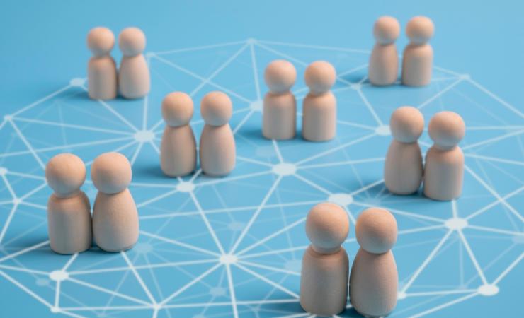 Pairs of wooden figures on a network pattern. Image via Shutterstock