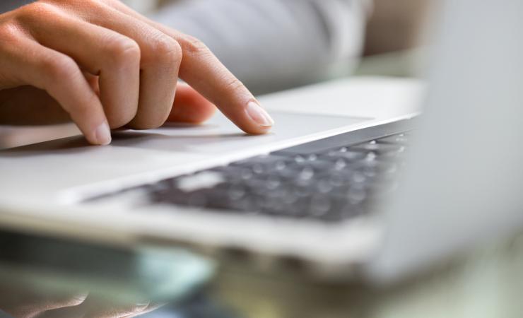 A close up of a woman using the mouse pad on a laptop. Image by LDprod via Shutterstock