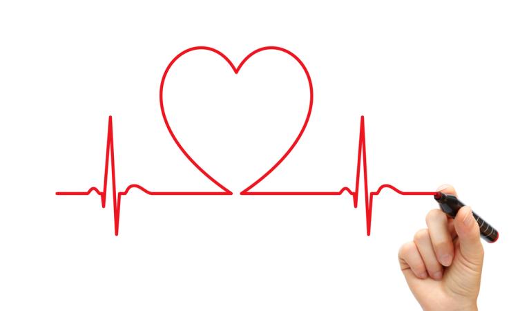 A person drawing an ECG style link with a red pen. Part of the line is shaped like a heart. Image by LeventeGyori via Shutterstock.