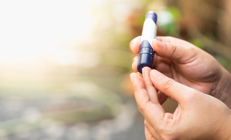 A woman pricks her finger to check her blood sugar levels. Image by Montri Thipsorn via Shutterstock.