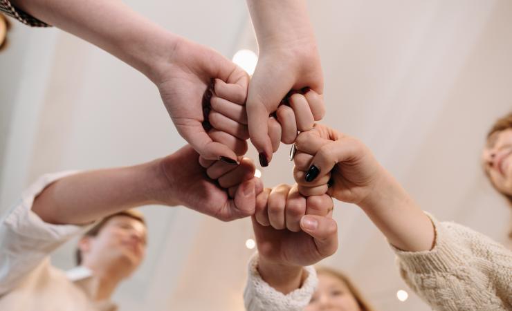 Five hands viewed from below doing a fist bump. Image by Pavel Danilyuk via Pexels.