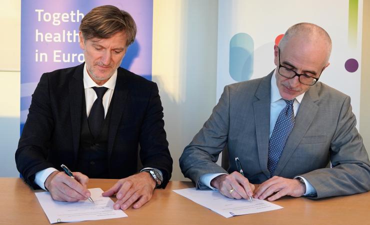 Jean-Marc Bourez, CEO of EIT Health, and Hugh Laverty, Executive Director ad interim of IHI JU, sign the Memorandum of Understanding. They are sitting next to each other at a table. Both are wearing suits and a tie. Image by IHI Programme Office.