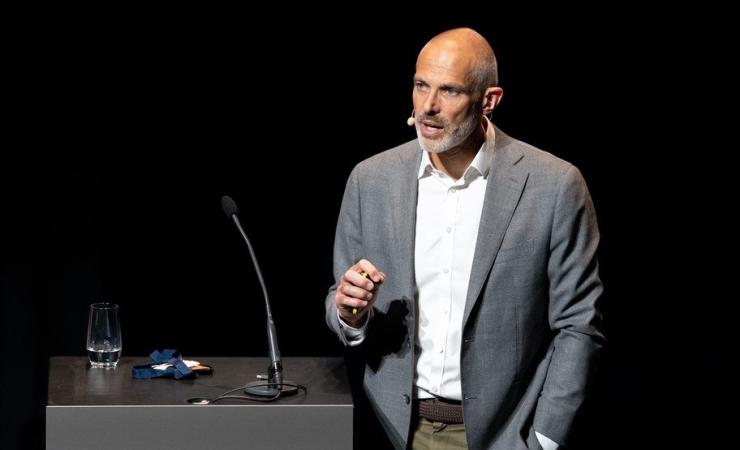 Niklas Blomberg speaking at an event last year. He is wearing a grey jacket and white shirt and is standing next to a black lectern with a microphone on it. Image courtesy of ELIXIR.