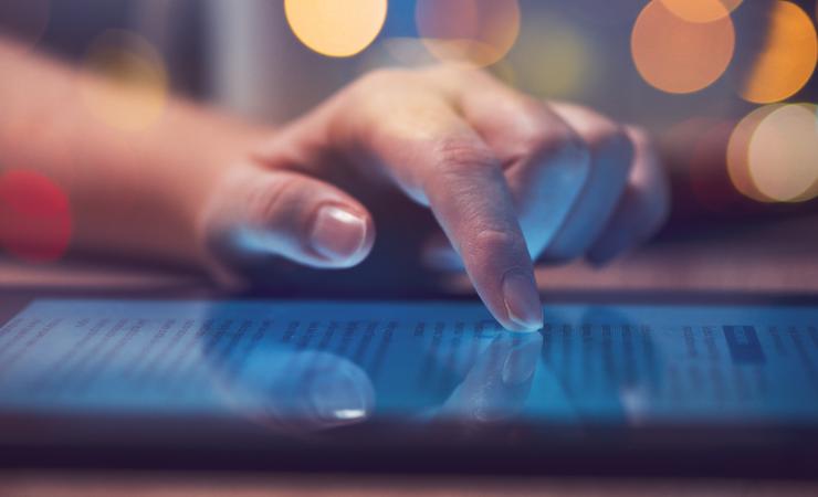 A close-up of a woman's hand scrolling on a tablet. Image by Bits And Splits via Shutterstock.