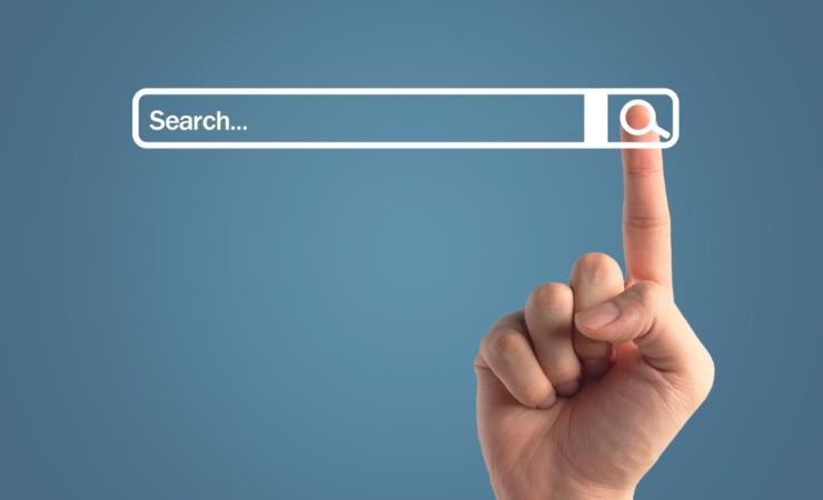 The index finger of a person clicking on a search button next to a search bar. Image by 19 Studio via Shutterstock.