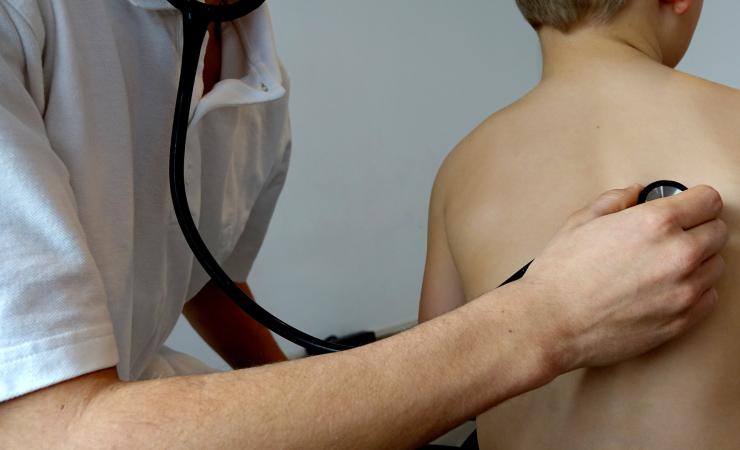 A doctor listens to a child's lungs via a stethoscope