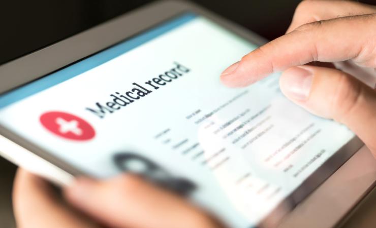 A close-up of a person holding a tablet. They are looking at their medical records. Image by Tero Vesalainen via Shutterstock.