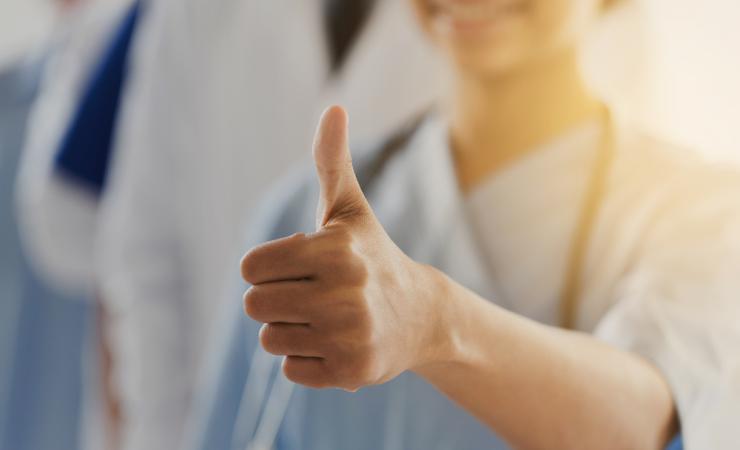 A health worker giving a thumbs up sign. Image by Syda Productions via Shutterstock