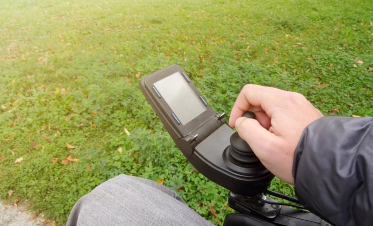 A close-up of the hand of a person driving an electric wheelchair. Image by 24kProduction via Shutterstock