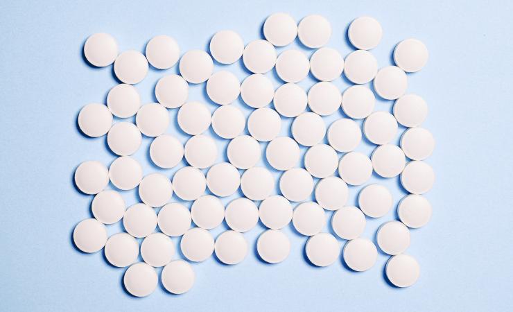 Round white pills on a pale blue background. Image by Anna Shvets via Pexels.