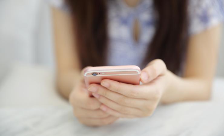 Close up of the hands of a woman holding a smartphone. Image by Piyato via Shutterstock