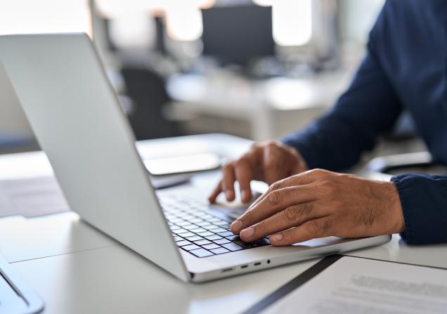 Bearded man hands typing on laptop keyboard. Image by insta_photos via Shutterstock.