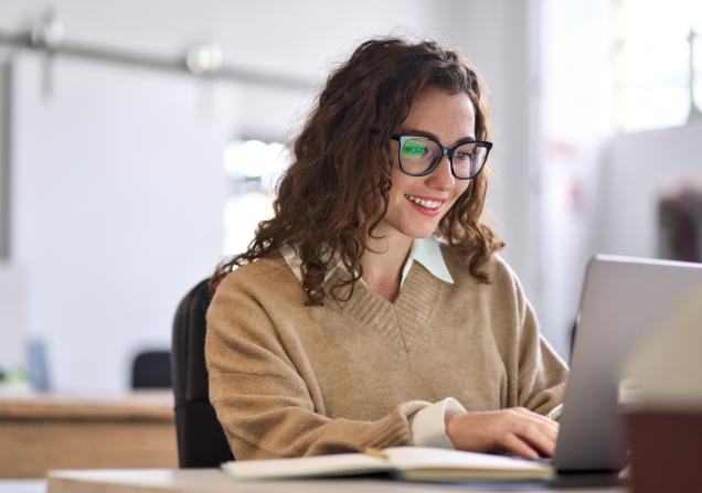Smiling female student using computer technology learning online, doing web research. Image by insta_photos via Shutterstock.