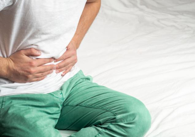 A person clutching their tummy in pain. Image by Zdan Ivan via Shutterstock.