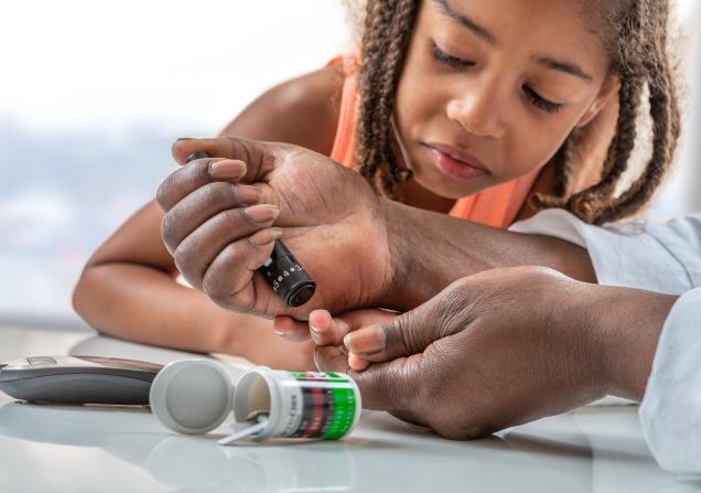 Child learning how to use a glucometer. Image credit: Adobe Stock