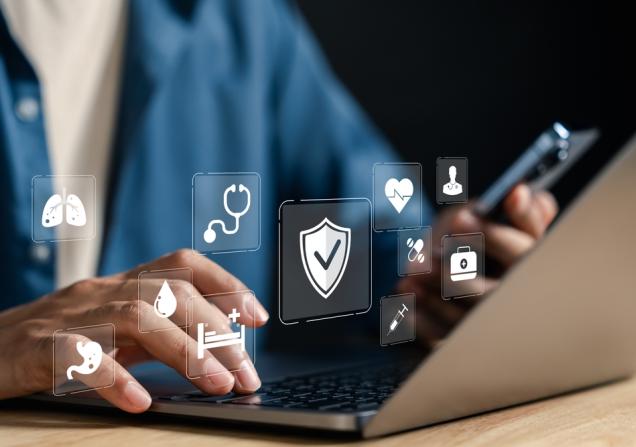 A person typing on a laptop. Health icons float above their hands, symbolising health data sharing. Image by MMD Creative, Shutterstock
