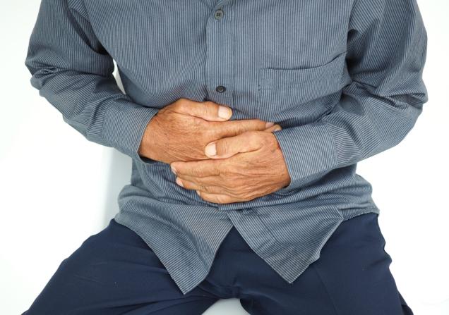 A man holding his hands against his stomach. Image by onstockphoto via Shutterstock.